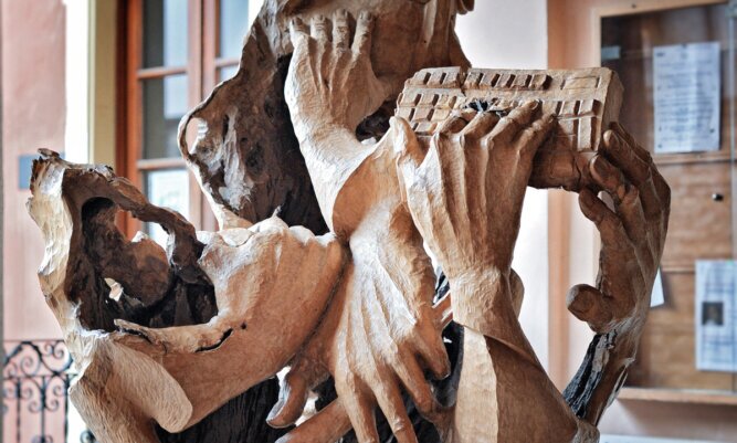 Es gibt nichts Gutes, außer: Man tut es Das Photo zeigt eine Holzskulptur mit vier verwinkelten Händen, die etwas tun, z.B.tippen.<br />©memephoto